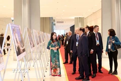 Đại biểu quốc tế tham quan trưng bày ảnh của Thông tấn xã Việt Nam tại Lễ mở ký Công ước Hà Nội, sáng 25/10. (Ảnh: Phương Hoa/TTXVN)