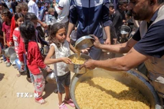Các em nhỏ xếp hàng chờ được phát thực phẩm cứu trợ tại Gaza. (Ảnh: THX/TTXVN)