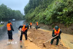 Bộ đội biên phòng thành phố Huế đào xúc đất đá, san gạt mặt đường bị sạt lở đất tại đèo Pê Kê, xã A Lưới 1. (Ảnh: Mai Trang/TTXVN)