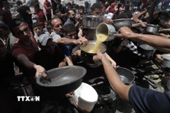 Người dân Palestine nhận thức ăn cứu trợ tại trại tị nạn Jabalia, miền Bắc Dải Gaza ngày 19/5. (Ảnh: THX/TTXVN)