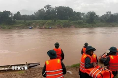 Các lực lượng chức năng triển khai công tác tìm kiếm thi thể chị H.T.H. (Ảnh: TTXVN phát)