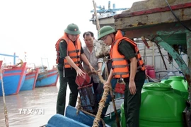 Lực lượng chức năng hướng dẫn, giúp ngư dân xã Hải Thịnh (Ninh Bình) phòng chống bão. (Ảnh: Thái Thuần/TTXVN)