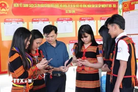 Đồng bào Xơ Đăng (xã Trà Linh, thành phố Đà Nẵng) theo dõi trên điện thoại các video clip, Inforgraphics hướng dẫn cách thức đi bỏ phiếu. (Ảnh: Trần Tĩnh/TTXVN)