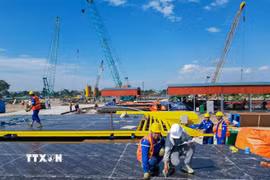 Công trường thi công dự án cầu Tứ Liên trên sông Hồng đang được triển khai với nhiều hạng mục nền móng, tập kết máy móc và vật liệu phục vụ thi công. Ảnh: Lê Đông - TTXVN