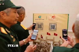 Các cựu chiến binh quét mã QR để xem triển lãm 3D trực tuyến “Hỡi đồng bào Thủ đô”. (Ảnh: Thanh Tùng/TTXVN)