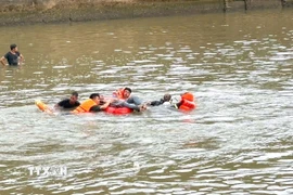 Lực lượng chức năng đưa thi thể nạn nhân đuối nước vào bờ. (Ảnh: TTXVN phát)