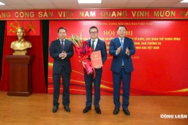 Phó Bí thư Đảng ủy Mặt trận Tổ quốc, các đoàn thể Trung ương Nguyễn Phi Long trao Quyết định và Phó Chủ tịch Thường trực Hội Nhà báo Việt Nam Nguyễn Đức Lợi tặng hoa chúc mừng đồng chí Lê Quốc Minh. (Nguồn: congluan.vn)