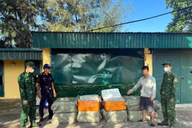 Đối tượng Nguyễn Văn Chung (áo trắng), sinh năm 1992 (trú tại khu phố Tràng Lộ, phường Móng Cái 1, tỉnh Quảng Ninh) cùng tang vật là số nầm lợn đông lạnh. (Nguồn: TTXVN)