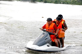Lực lượng tình nguyện viên hỗ trợ di dời khẩn cấp người dân bị ngập đến nơi an toàn. (Ảnh: Nguyễn Thanh/TTXVN)
