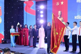 Tổng Bí thư Tô Lâm gắn Huân chương Hồ Chí Minh lên lá cờ truyền thống Thông tấn xã Việt Nam. (Ảnh: Lâm Khánh/TTXVN)