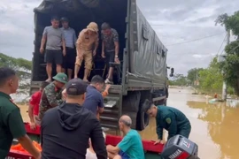 Do nhiều tuyến đường trong thôn An Lạc, xã Trung Giã (Hà Nội) đã ngập sâu, lực lượng chức năng dùng thuyền và ô tô chuyên dụng đưa người dân di tản an toàn. (Ảnh: TTXVN phát)
