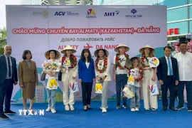 Ban Tổ chức tặng hoa, quà cho các hành khách đầu tiên đến Đà Nẵng trên đường bay trực tiếp từ Kazakhstan. (Ảnh: Trần Lê Lâm/TTXVN)