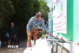 Người dân xã Vĩnh Châu nhận nước sạch miễn phí. (Ảnh: Thu Hiền/TTXVN)