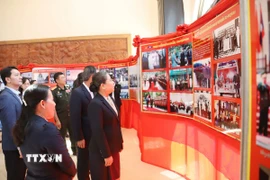 Bộ trưởng Bộ Thông tin, Văn hóa và Du lịch Lào Suansavanh Viyaket cùng các đại biểu tham quan Triển lãm ảnh. (Ảnh: Xuân Tú/TTXVN)