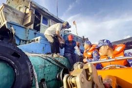 Lực lượng cảnh sát biển tiếp cận tàu cá, đón ngư dân lên tàu cấp cứu. (Ảnh minh họa: TTXVN phát)