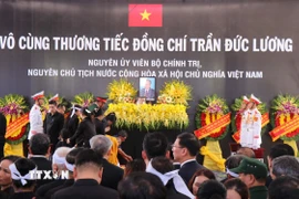 Nghi lễ thả hoa vào huyệt. (Ảnh: Phạm Cường/TTXVN)