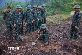 Các thành viên Đội tìm kiếm, quy tập hài cốt Liệt sĩ sử dụng máy dò mìn để đảm bảo khu vực tìm kiếm "sạch" trước khi tiến hành tìm kiếm. Ảnh: Hoàng Hiếu - TTXVN