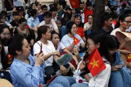 Nhiều bạn trẻ tranh thủ “check-in” cùng cờ Tổ quốc trong khi chờ đợi diễu binh, diễu hành. (Ảnh: Tiến Lực/TTXVN)