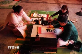 Trình diễn thư pháp tặng chữ tại Chương trình “Tết Hoàng cung” ở Đại Nội Huế. (Ảnh: Nguyên Lý/TTXVN)