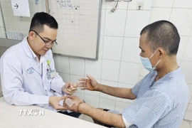 Bác sỹ kiểm tra hai bàn tay được nối thành công của nạn nhân. (Ảnh: TTXVN phát)