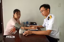 Bác sĩ tại Bệnh xá quân y đảo Sinh Tồn thăm khám cho người dân trên đảo. (Ảnh: Hữu Quyết/TTXVN)