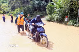 Hỗ trợ người dân ra khỏi vùng ngập lụt tại xã Mường Hung. (Ảnh: Quang Quyết/TTXVN)