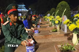 Đoàn viên thanh niên thắp nến tri ân lên các phần mộ liệt sỹ tại Nghĩa trang A1. (Ảnh: Xuân Tư/TTXVN)