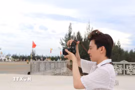 Một bạn trẻ sử dụng máy ảnh để ghi lại cảnh đẹp, làm video đưa lên các nền tảng xã hội. (Ảnh: Đinh Hương/TTXVN)