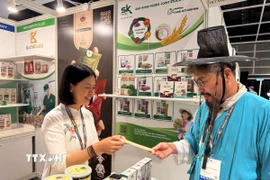 Khách tìm hiểu về sản phẩm ống hút gạo của Việt Nam. (Ảnh: Mạc Luyện/TTXVN)