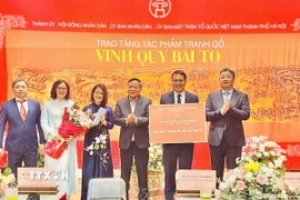 Lãnh đạo thành phố Hà Nội trao chứng nhận tặng tác phẩm tranh gỗ "Vinh Quy Bái Tổ" cho Trung tâm Hoạt động Văn hóa Khoa học Văn Miếu - Quốc Tử Giám. (Ảnh: Tuyết Mai/TTXVN)