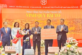 Lãnh đạo thành phố Hà Nội trao chứng nhận tặng tác phẩm tranh gỗ "Vinh Quy Bái Tổ" cho Trung tâm Hoạt động Văn hóa Khoa học Văn Miếu - Quốc Tử Giám. (Ảnh: Tuyết Mai/TTXVN)