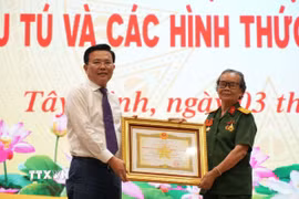 Ông Nguyễn Thanh Hải, Phó Bí thư Tỉnh ủy, Chủ tịch Ủy ban Mặt trận Tổ quốc Việt Nam tỉnh Tây Ninh, trao Danh hiệu Anh hùng lực lượng vũ trang của Chủ tịch nước cho bà Phan Thị Út. (Ảnh: Thanh Bình/TTXVN)