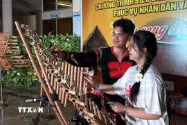 Sinh viên Việt Nam ở nước ngoài trải nghiệm nhạc cụ đàn T'rưng. (Ảnh: Tường Quân/TTXVN)