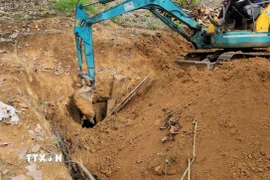 Lực lượng chức năng sử dụng các phương tiện máy xúc để dọn dẹp, lấp một hầm khai thác vàng. (Ảnh: Đậu Tất Thành/TTXVN).