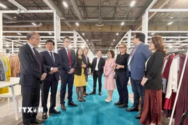 Đại sứ Việt Nam tại Pháp Đinh Toàn Thắng, đại diện Ban tổ chức và các đơn vị hỗ trợ trao đổi với các doanh nghiệp Việt Nam tham dự Triển lãm. (Ảnh: Hữu Chiến/TTXVN)