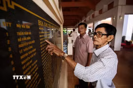 Trở lại chiến khu xưa, những đồng đội cũ lặng lẽ dừng chân trước bia tưởng niệm, tìm lại tên những người đồng chí đã anh dũng ngã xuống. (Ảnh: Giang Phương/TTXVN)
