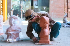 Người thợ căn chỉnh lại bức tượng truyền thần trước khi chuyển sang công đoạn đúc sản phẩm. (Ảnh: Công Luật/TTXVN)