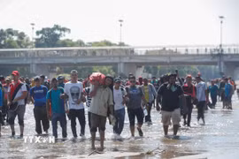Người di cư vượt sông Suchiate từ Guatemala để tới Mexico, trong hành trình đến Mỹ. (Ảnh: THX/TTXVN)