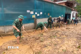 Cán bộ, chiến sỹ Đồn biên phòng Mường Ải (Nghệ An) giúp người dân địa phương dọn dẹp bùn đất, khắc phục hậu quả mưa lũ. (Ảnh: TTXVN phát) 