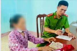 Cán bộ Công an xã Vũ Quý, tỉnh Hưng Yên vận động, giải thích cho bà L. trú tại thôn Đồng Vàng hiểu, tránh rơi vào bẫy của kẻ lừa đảo. (Ảnh: TTXVN phát) 