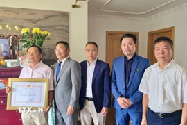 Tham tán Công xứ Chu Tuấn Đức (đứng giữa), Chủ tịch Hội Cựu chiến binh Việt Nam tại Cộng hòa Liên bang Đức trao giấy khen, tri ân công lao của gia đình ông Lê Đình Bính (đứng đầu) có người thân là liệt sỹ. (Ảnh: Phương Hoa/TTXVN)