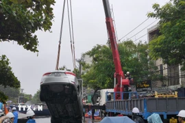 Lực lượng chức năng cẩu xe ô tô từ dưới hố lên. (Ảnh: Quốc Dũng/TTXVN)