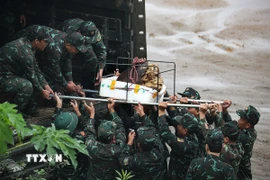 Lực lượng cán bộ chiến sỹ di chuyển đầu nổ quả bom có trọng lượng gần 1000kg lên xe để chuyển đi hủy nổ. (Ảnh: Trọng Đạt/TTXVN)