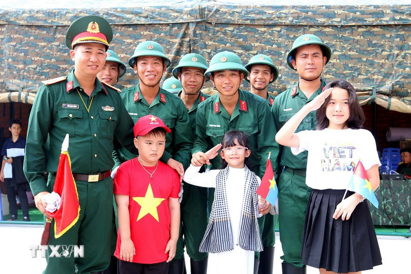 Các em thiếu nhi chụp ảnh lưu niệm với các chiến sỹ Đội pháo lễ, Lữ đoàn 96, Binh chủng pháo binh sau giờ luyện tập bắn đại bác tại công viên Bến Bạch Đằng, Quận 1, Thành phố Hồ Chí Minh. (Ảnh: Thanh Vũ/TTXVN)