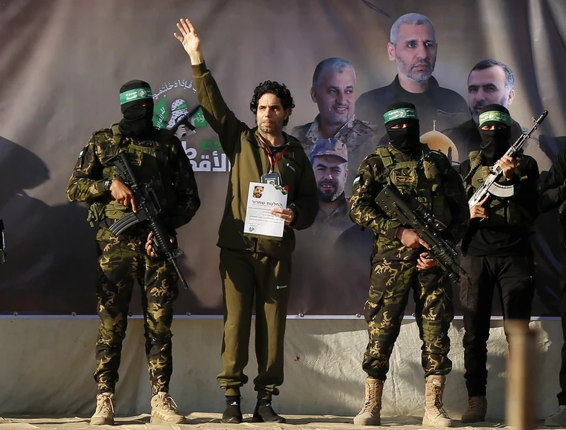 Các thành viên Lữ đoàn Al-Qassam Brigades, cánh quân của Hamas, bàn giao con tin Ofer Calderon (thứ 2, trái) cho Ủy ban Chữ Thập đỏ quốc tế tại thành phố Gaza ngày 1/2/2025. (Ảnh: Anadolu Agency/TTXVN)