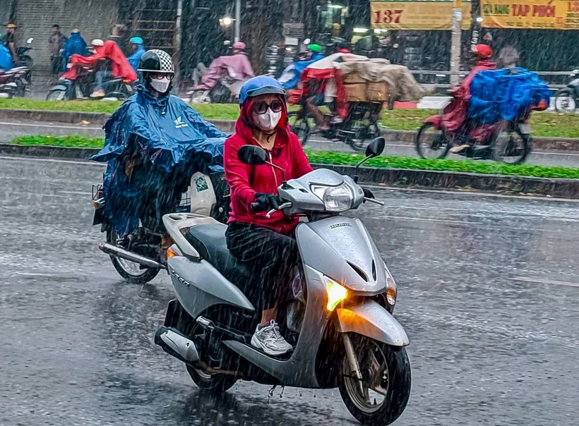 Mưa đột ngột sau một ngày nắng không gợn mây khiến nhiều người dân bất ngờ, không kịp chuẩn bị. (Ảnh: TTXVN phát)