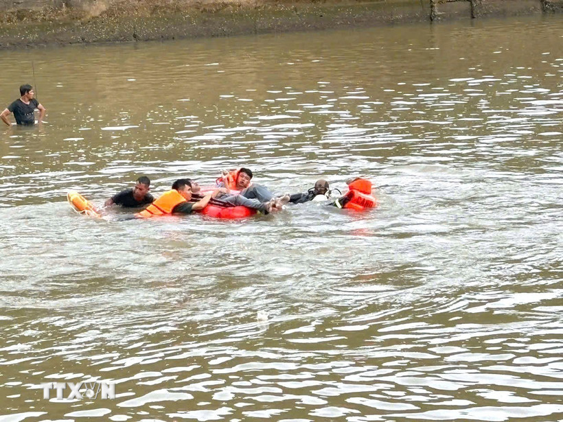 Lực lượng chức năng đưa thi thể nạn nhân đuối nước vào bờ. (Ảnh: TTXVN phát)