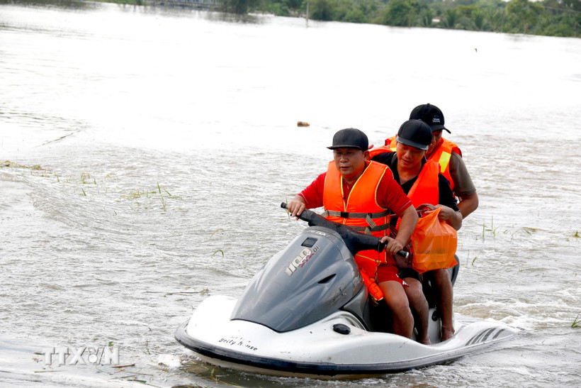 Lực lượng tình nguyện viên hỗ trợ di dời khẩn cấp người dân bị ngập đến nơi an toàn. (Ảnh: Nguyễn Thanh/TTXVN)