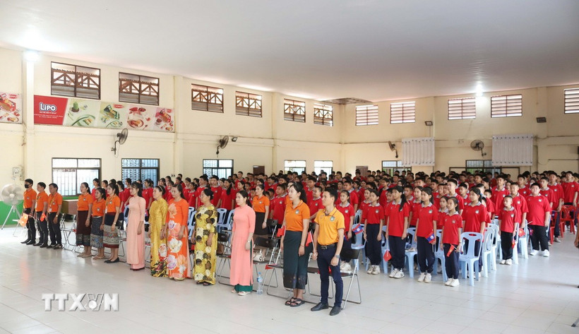 Thầy trò Trường song ngữ Lào-Việt Nam Nguyễn Du thực hiện nghi thức Chào cờ trước giờ xem truyền hình trực tiếp Lễ kỷ niệm 50 năm Giải phóng miền Nam, thống nhất đất nước.(Ảnh: Xuân Tú/TTXVN)