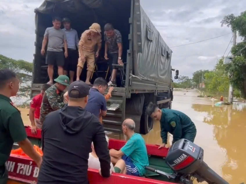 Do nhiều tuyến đường trong thôn An Lạc, xã Trung Giã (Hà Nội) đã ngập sâu, lực lượng chức năng dùng thuyền và ô tô chuyên dụng đưa người dân di tản an toàn. (Ảnh: TTXVN phát)